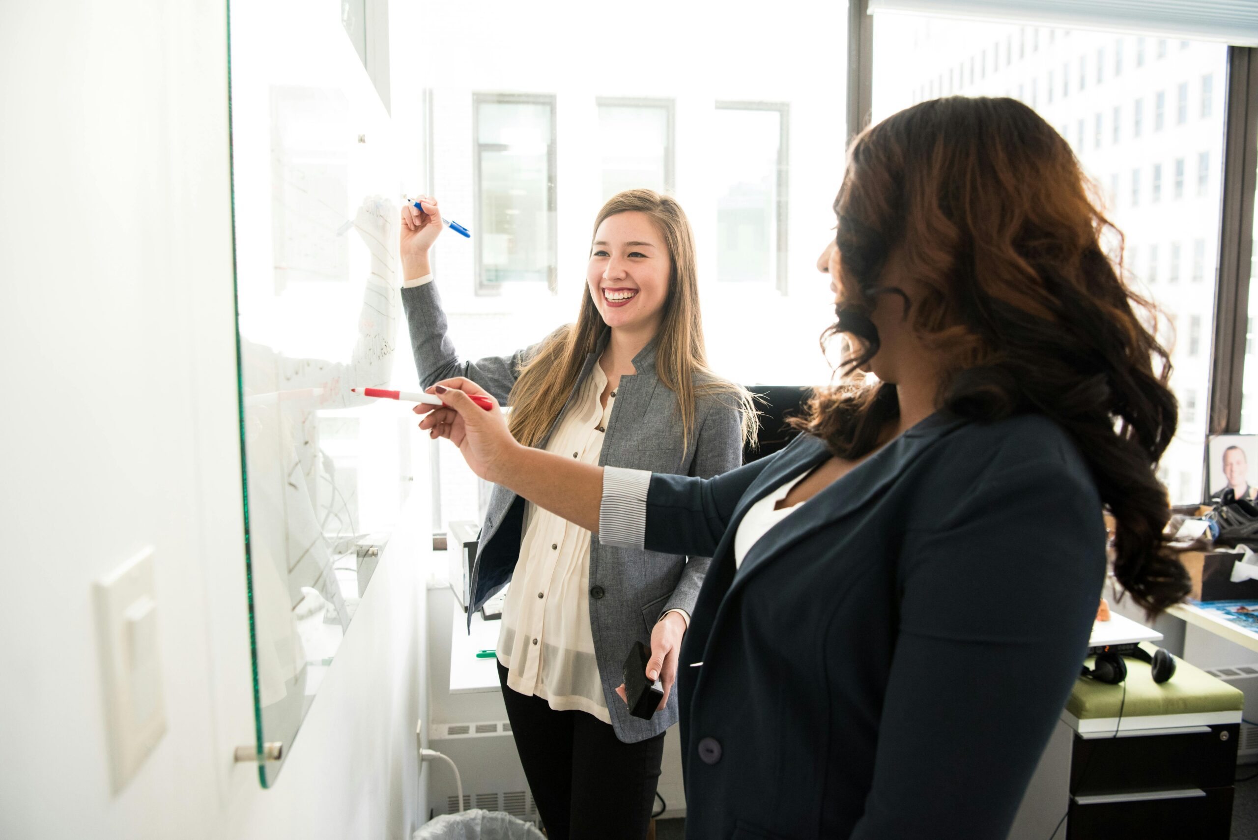 Two people working beside a whiteboard.